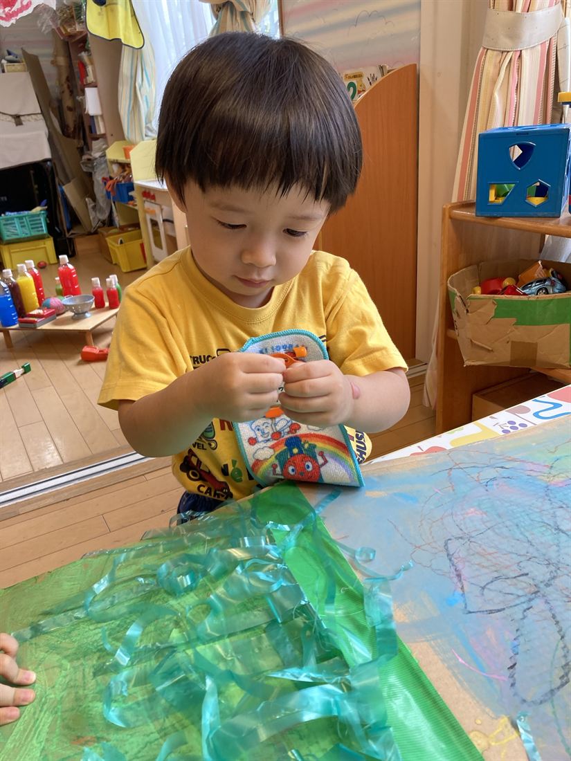 緑のテープの素材を、子どもが手でじっと確かめている